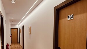 A hotel hallway with wooden flooring, a fire extinguisher, and doors numbered 504 and 507. - Hostal Abadía Madrid (Madrid)