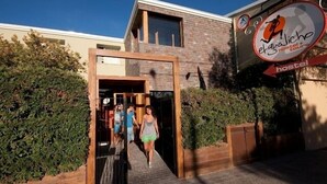 A hostel entrance with a wooden frame and glass doors, a sign for 'El Galich Hostel Tours', and a clear sky. - El Gualicho Hostel (Puerto Madryn)