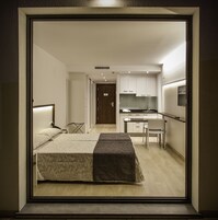 Una habitación de hotel moderna con una cama, un escritorio y una kitchenette.