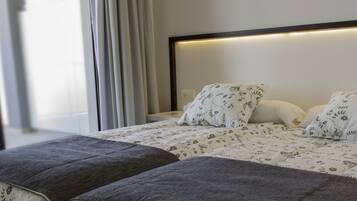 Una cama bien hecha con ropa de cama floral, una mesita de noche y una ventana con cortinas.