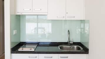 A modern kitchen with white cabinets, a black countertop, and a stainless steel sink.