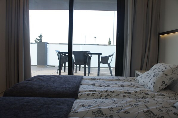 A room with a bed, a small table, and two chairs. There is a balcony with a view of the water. - Hotel Playa Oliva (Oliva)