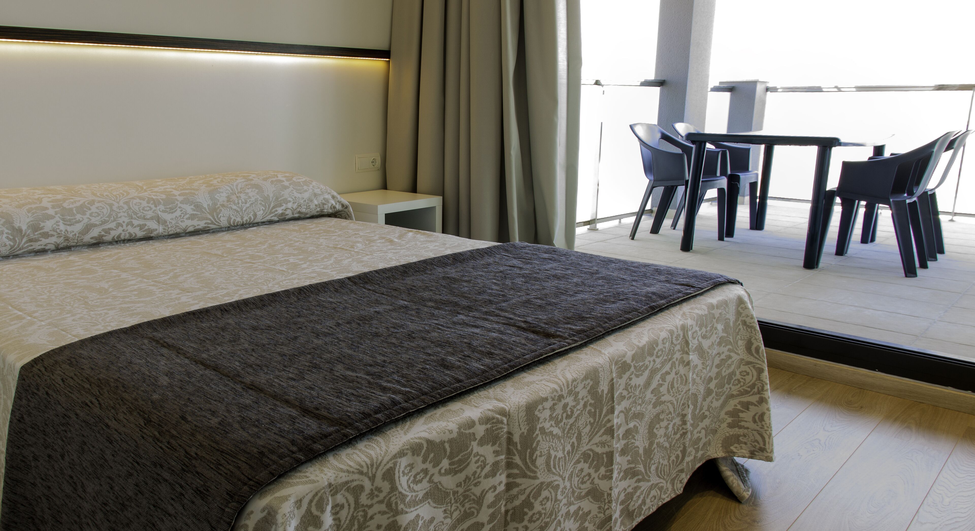 A hotel room with a bed, a small table, and chairs.
