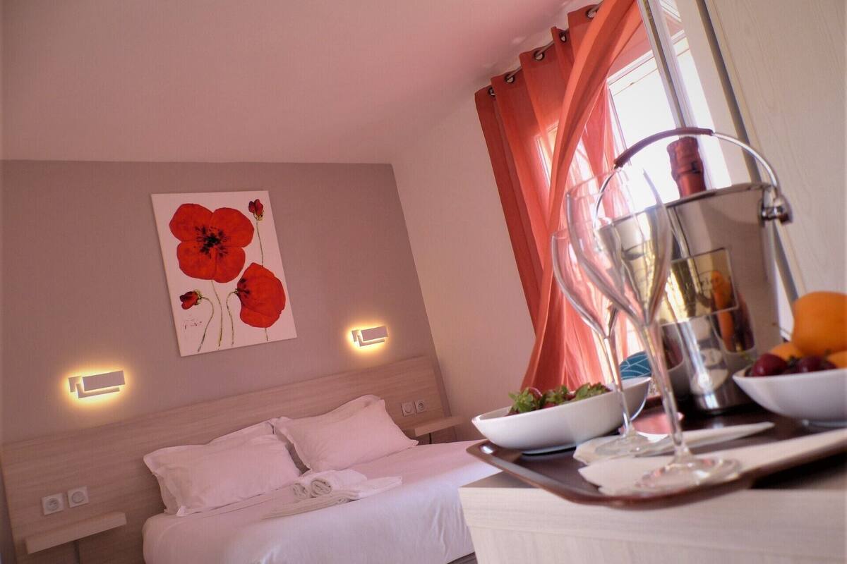 A hotel room with a bed, bedside table, and a wall-mounted light.