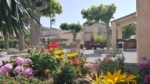A garden area with various plants and flowers, outdoor seating, and a stone structure. - Stella Marina (Rogliano)