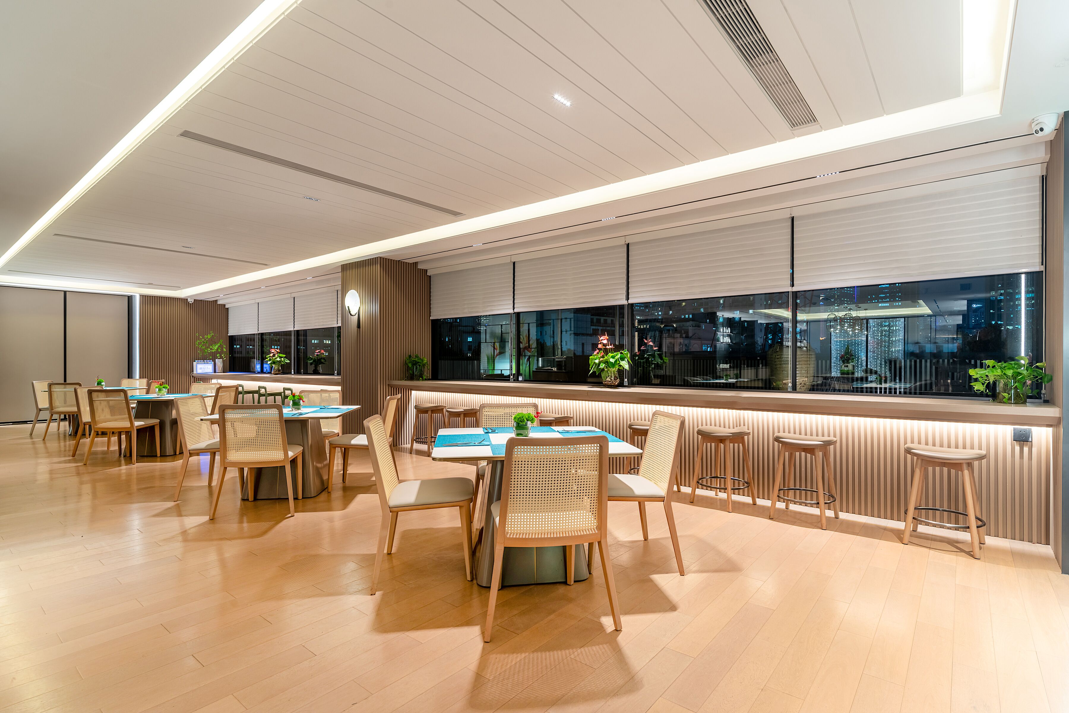 Un comedor moderno con suelo de madera, mesas y sillas.