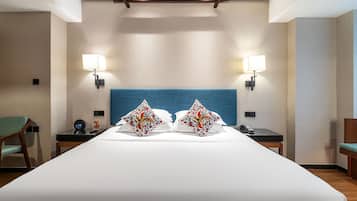 A hotel room with a large bed, two bedside tables, a chair, and two wall-mounted lamps.