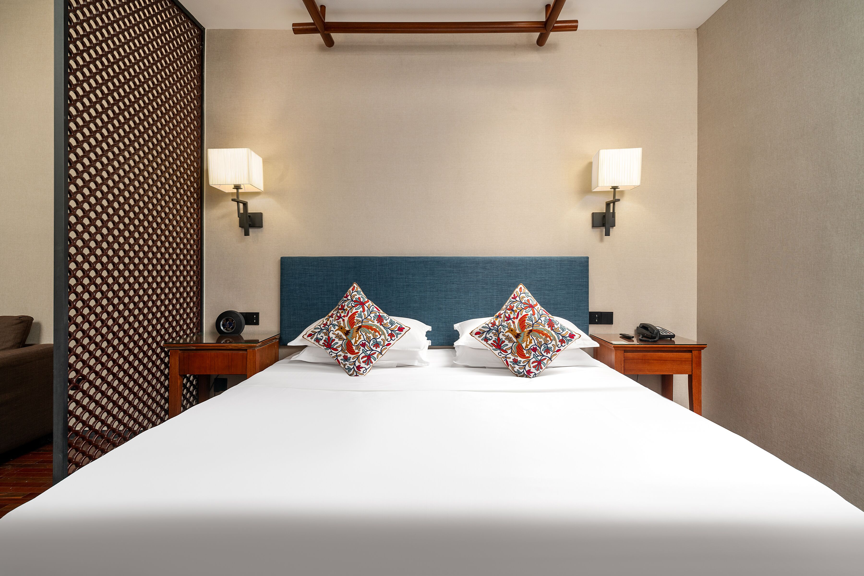 Ein Hotelzimmer mit einem großen Bett, zwei Nachttischen, einem blauen Kopfteil und Wandverkleidungen mit Muster.