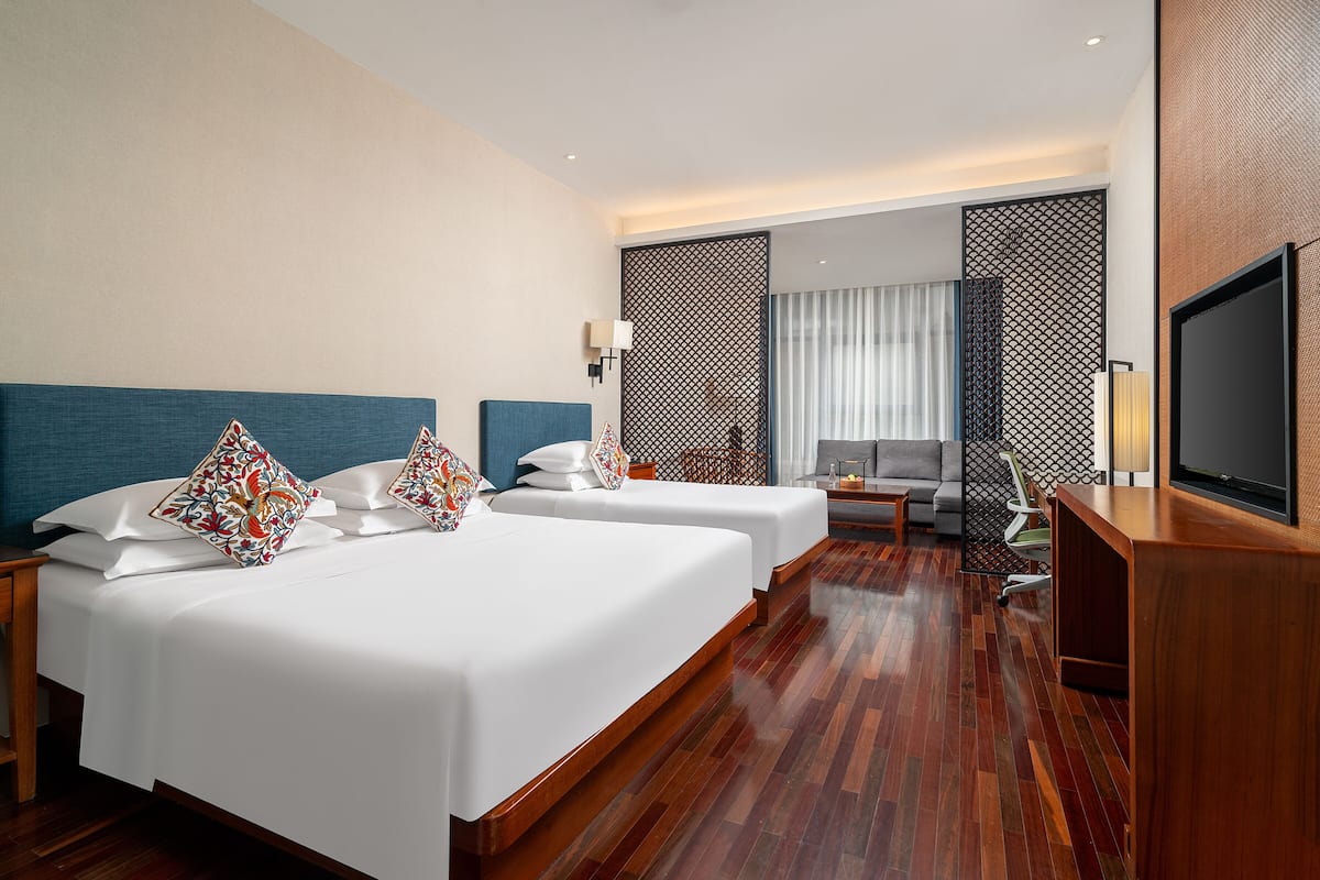 Een hotelkamer met twee bedden, een bureau, een televisie en een zithoek.
