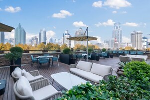 A rooftop patio with outdoor furniture, a pergola, and a city skyline view.