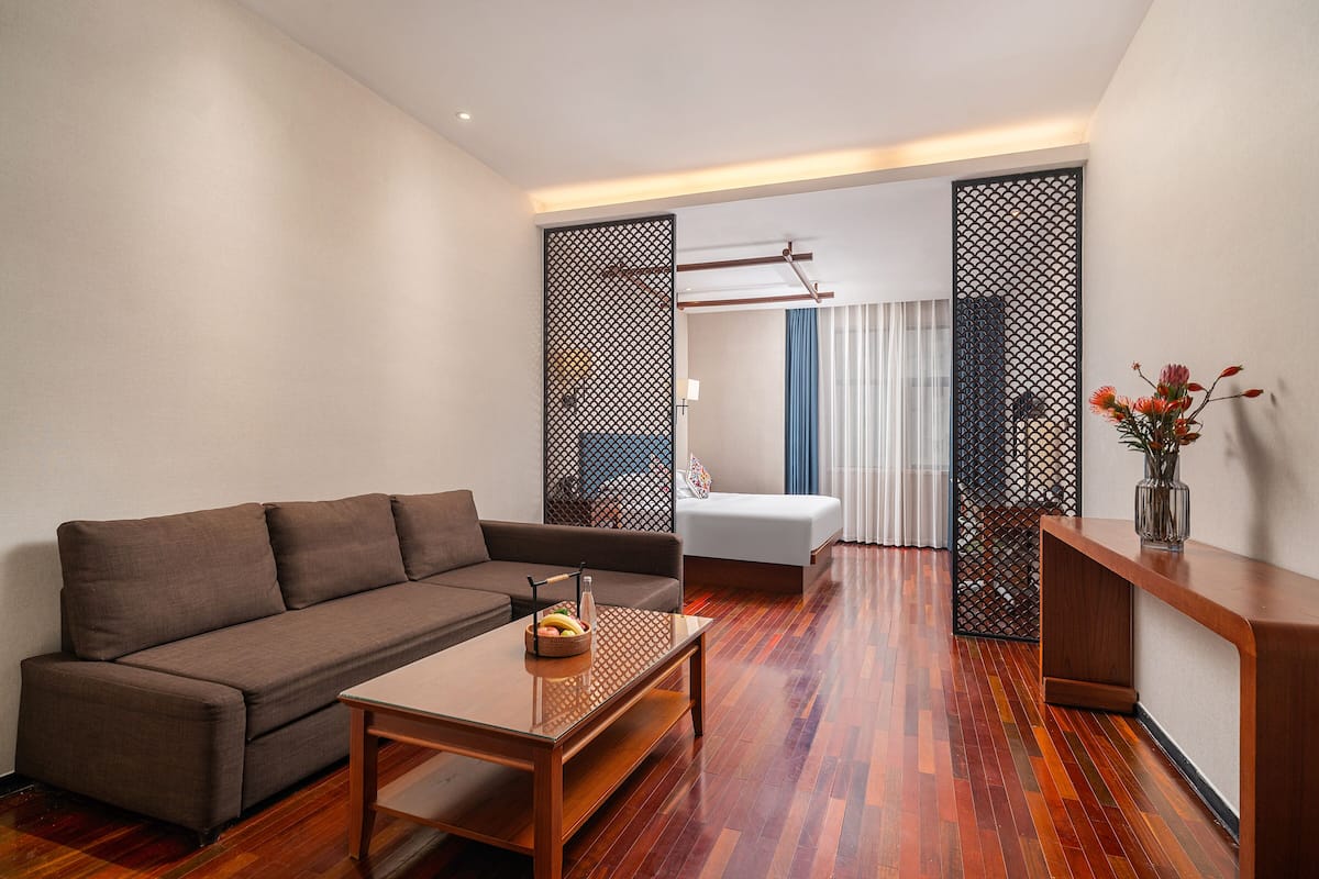 Een moderne woonkamer met een bruine bank, een houten salontafel en een houten console met een vaas.