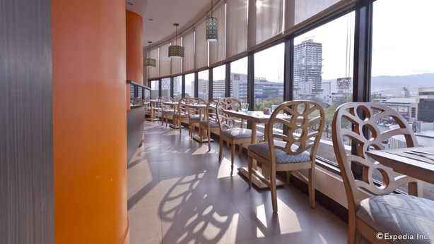 Un restaurant moderne doté de hauts plafonds et de grandes fenêtres offrant une vue sur la ville.