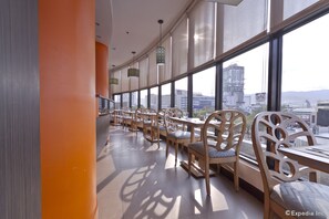Un restaurante moderno con techos altos y ventanas amplias que ofrecen vistas a la ciudad.