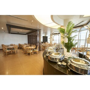 A buffet area with round tables and chairs, a large potted plant, and a modern ceiling design. - Summit Circle Cebu (Cebu City)