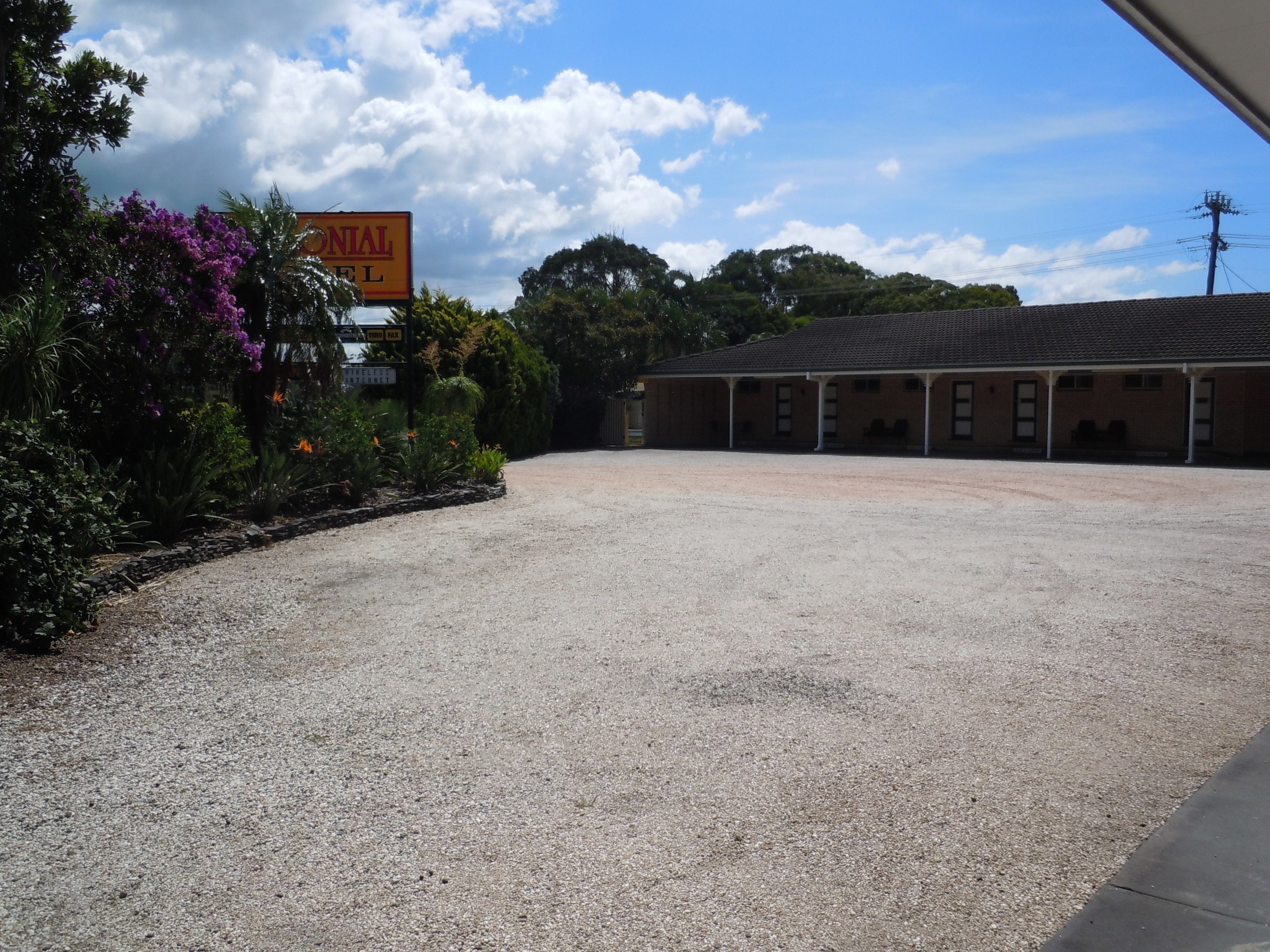 A building with a gravel driveway and a sign indicating a motel.