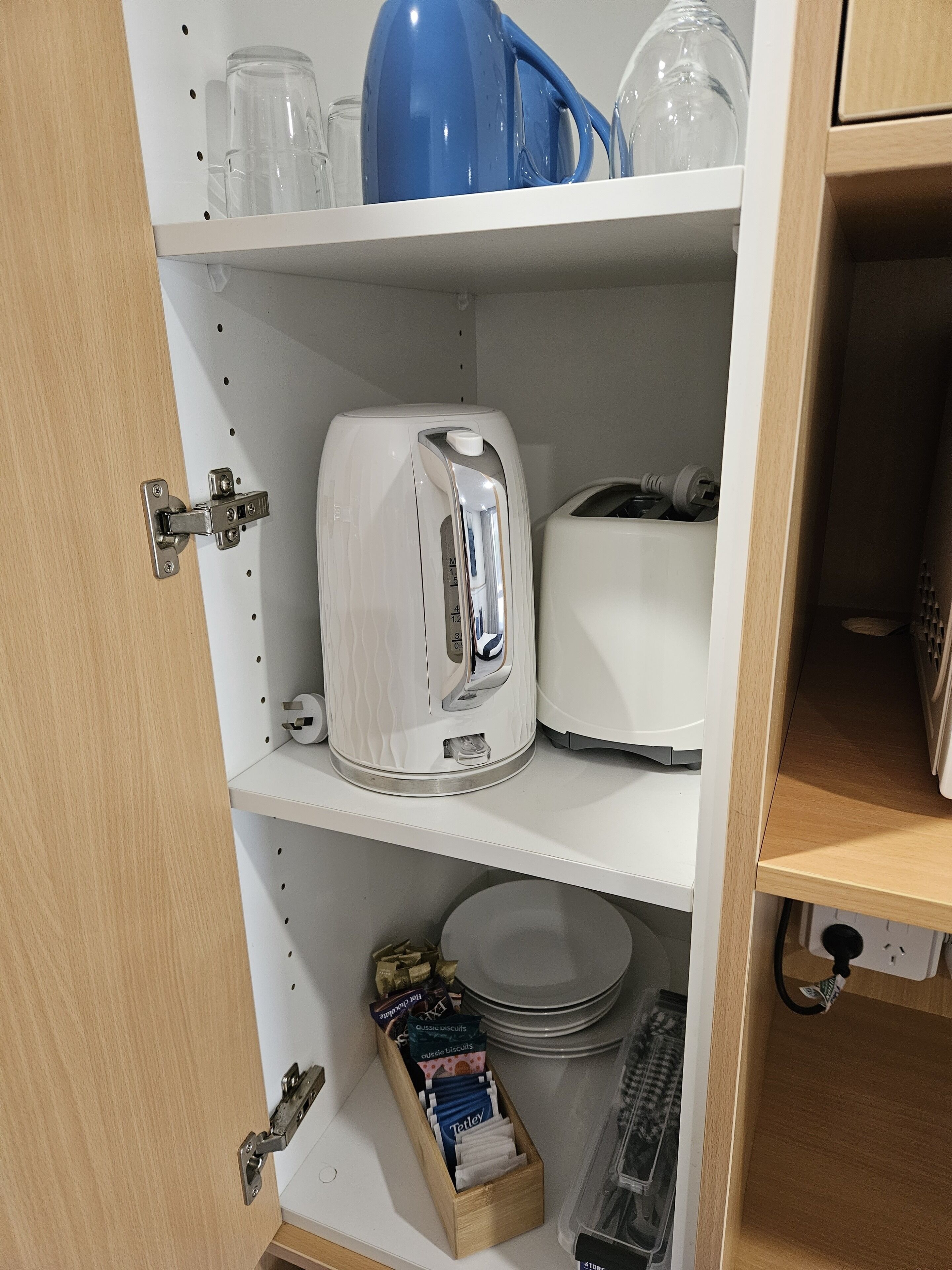 Una cocina con tostadora, hervidor y un cajón con bolsitas de té y galletas.