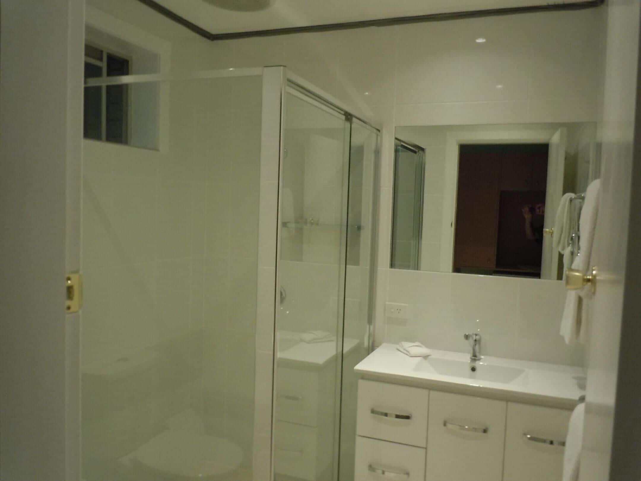 A modern bathroom with a glass shower enclosure, a white vanity with a mirror, and a sink.