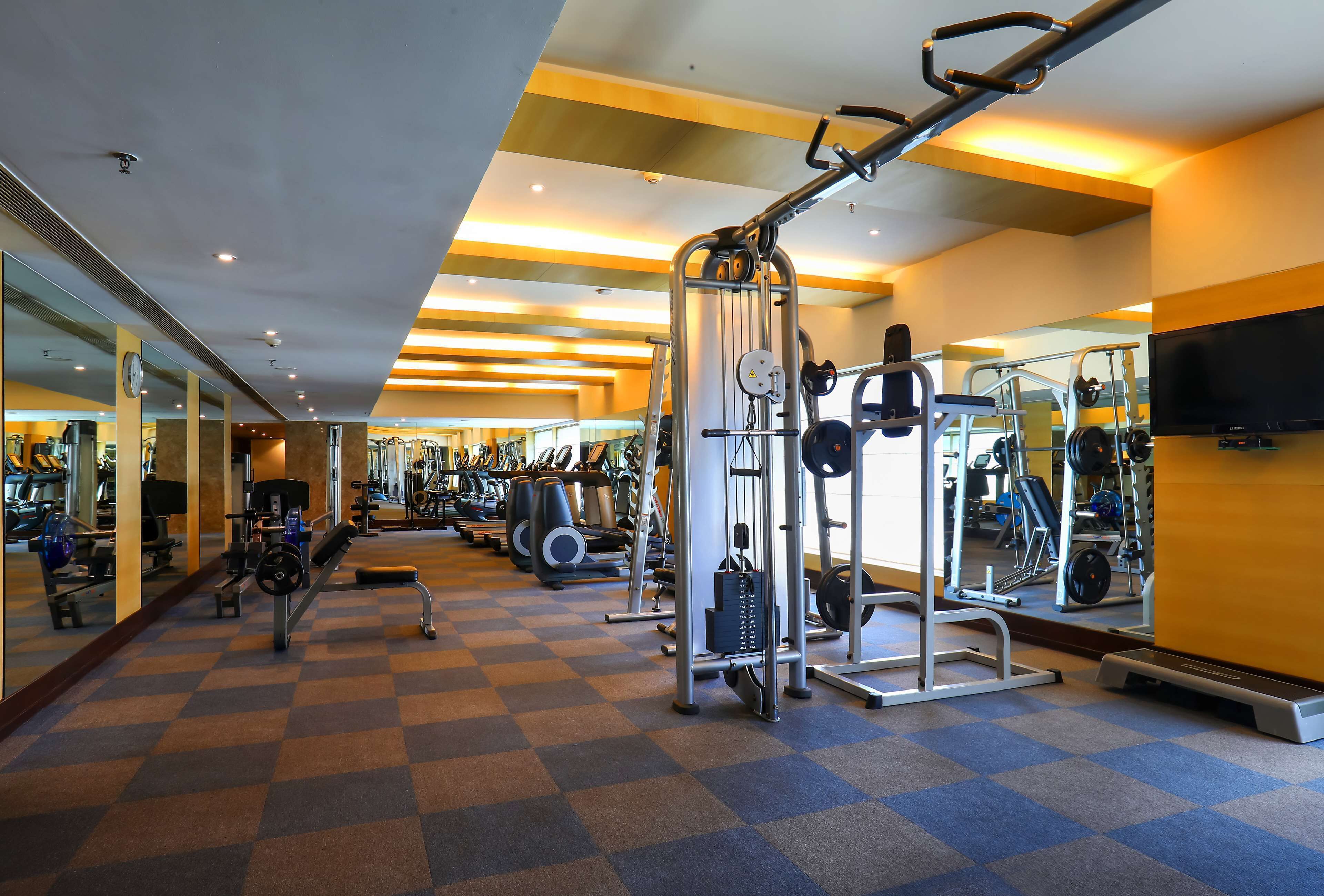 A gym with various exercise equipment, a mirrored wall, and a checkered floor.