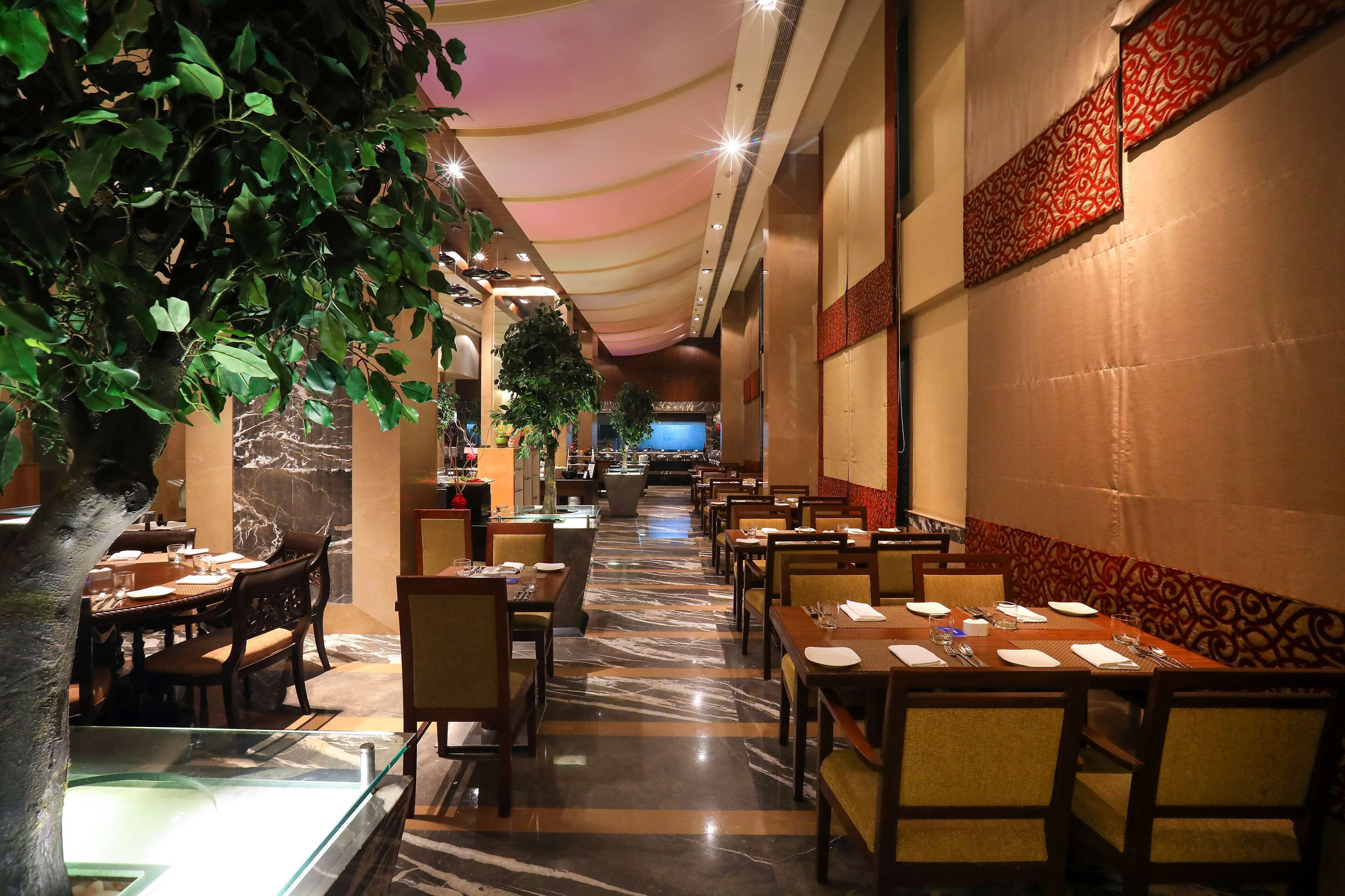 A restaurant with marble flooring, tables set with white tablecloths, and a ceiling with a draped fabric design.