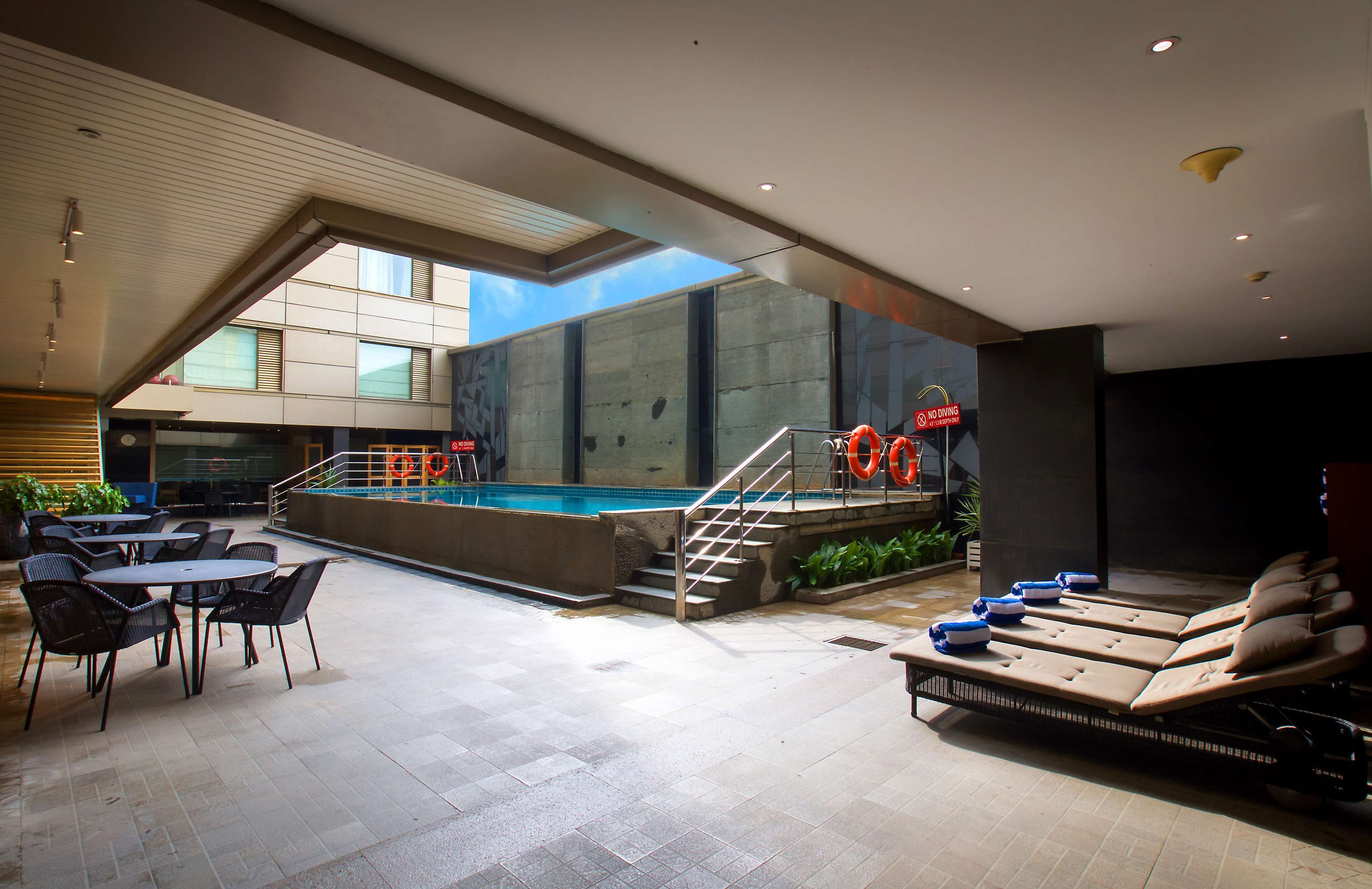 An indoor swimming pool area with lounge chairs, a poolside table, and a staircase leading to a deck.