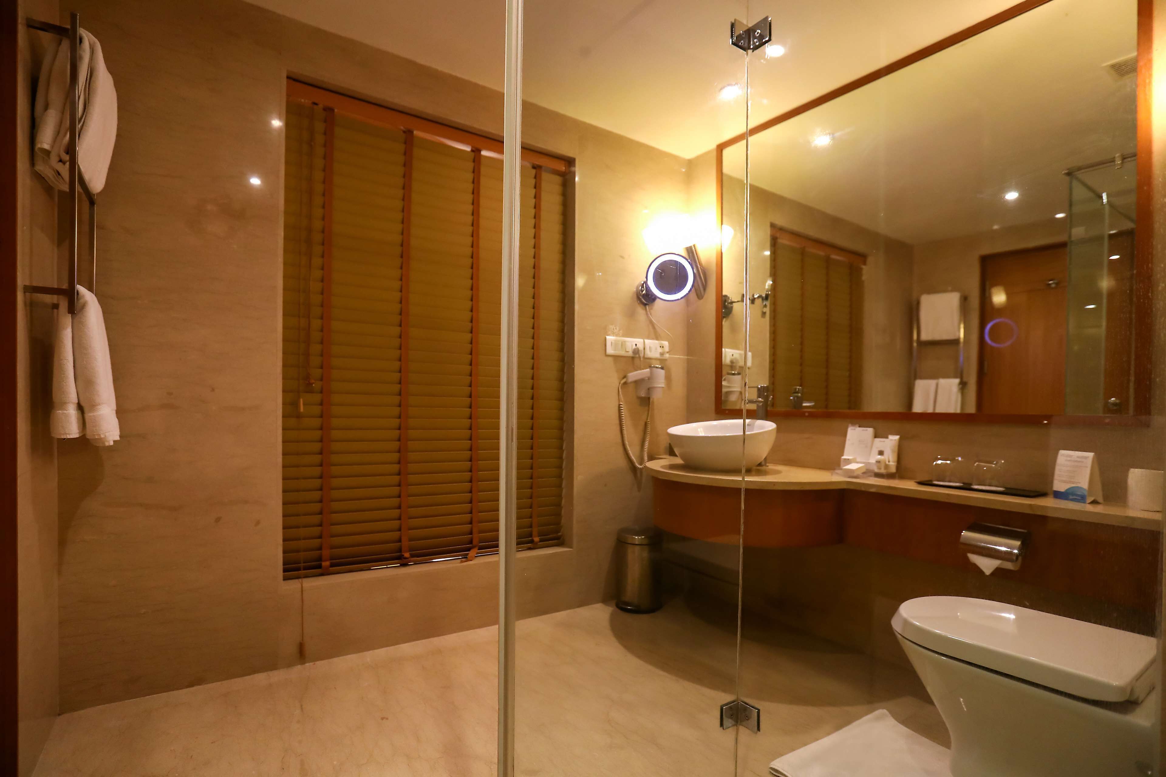 A modern bathroom with a glass shower enclosure, a white sink, and a large mirror.