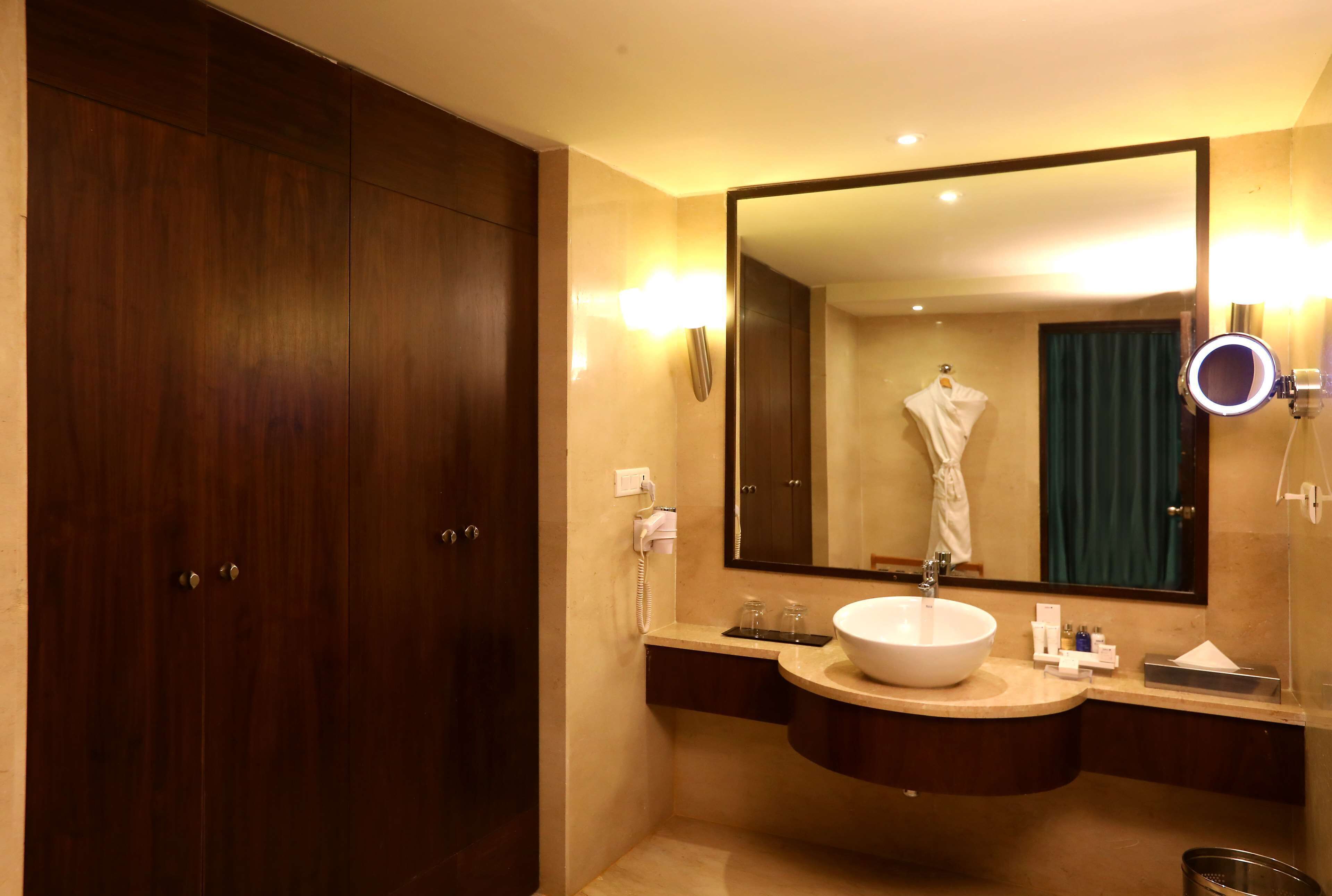 Un baño moderno con un espejo grande, un tocador redondo y un armario de madera.