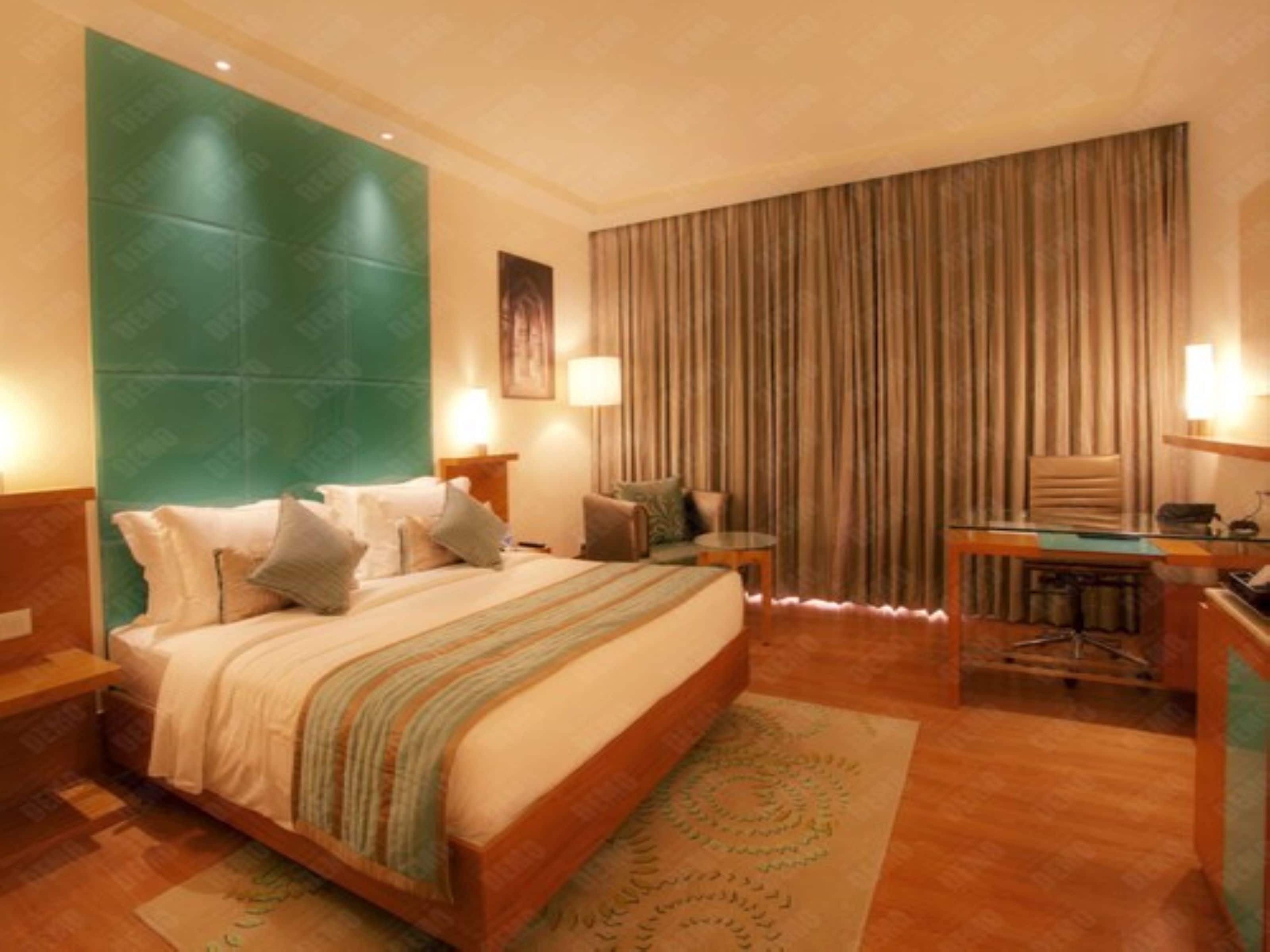 A hotel room with a large bed, a desk, a chair, and a curtain.