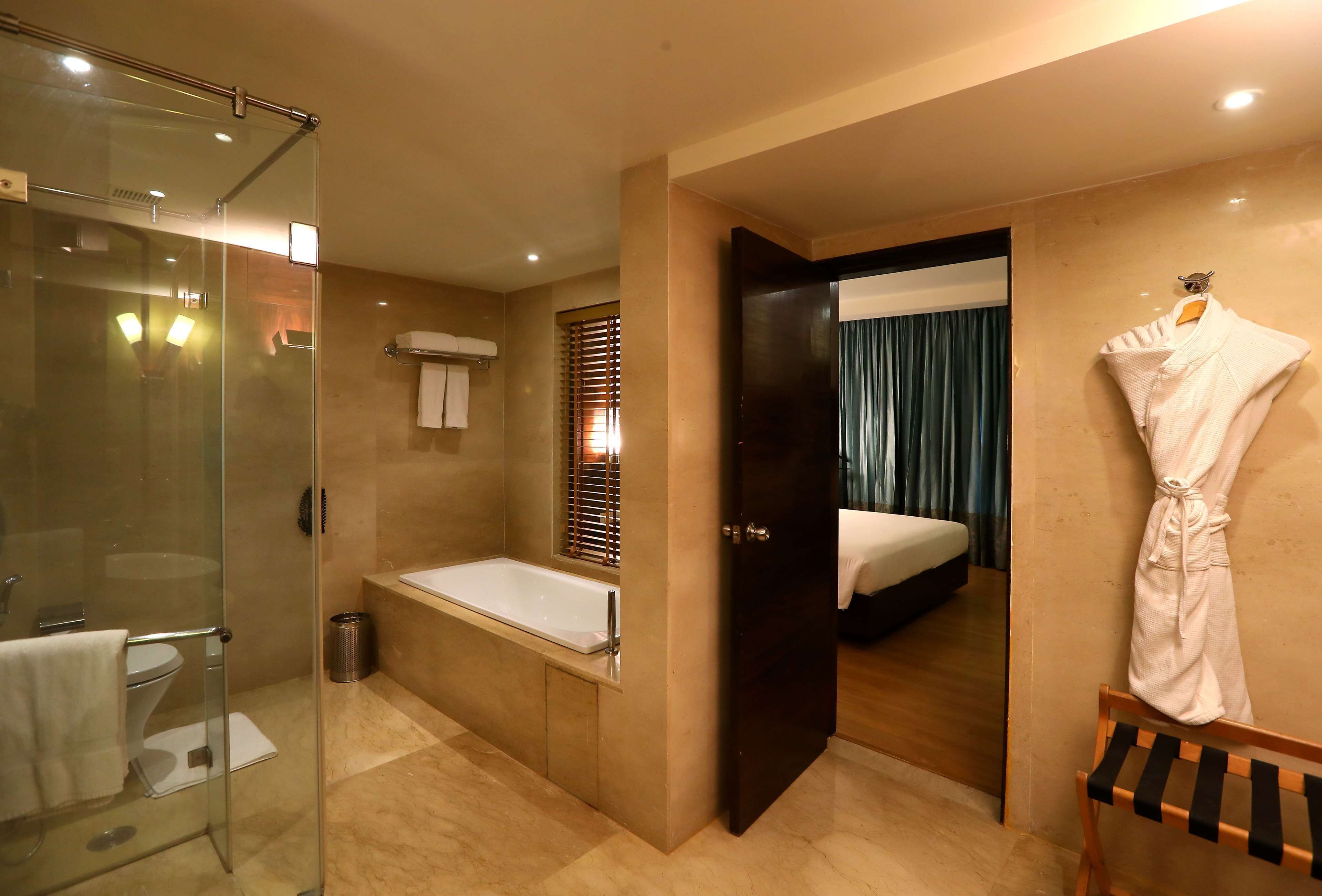 A hotel bathroom with a glass-enclosed shower, a bathtub, and a toilet.