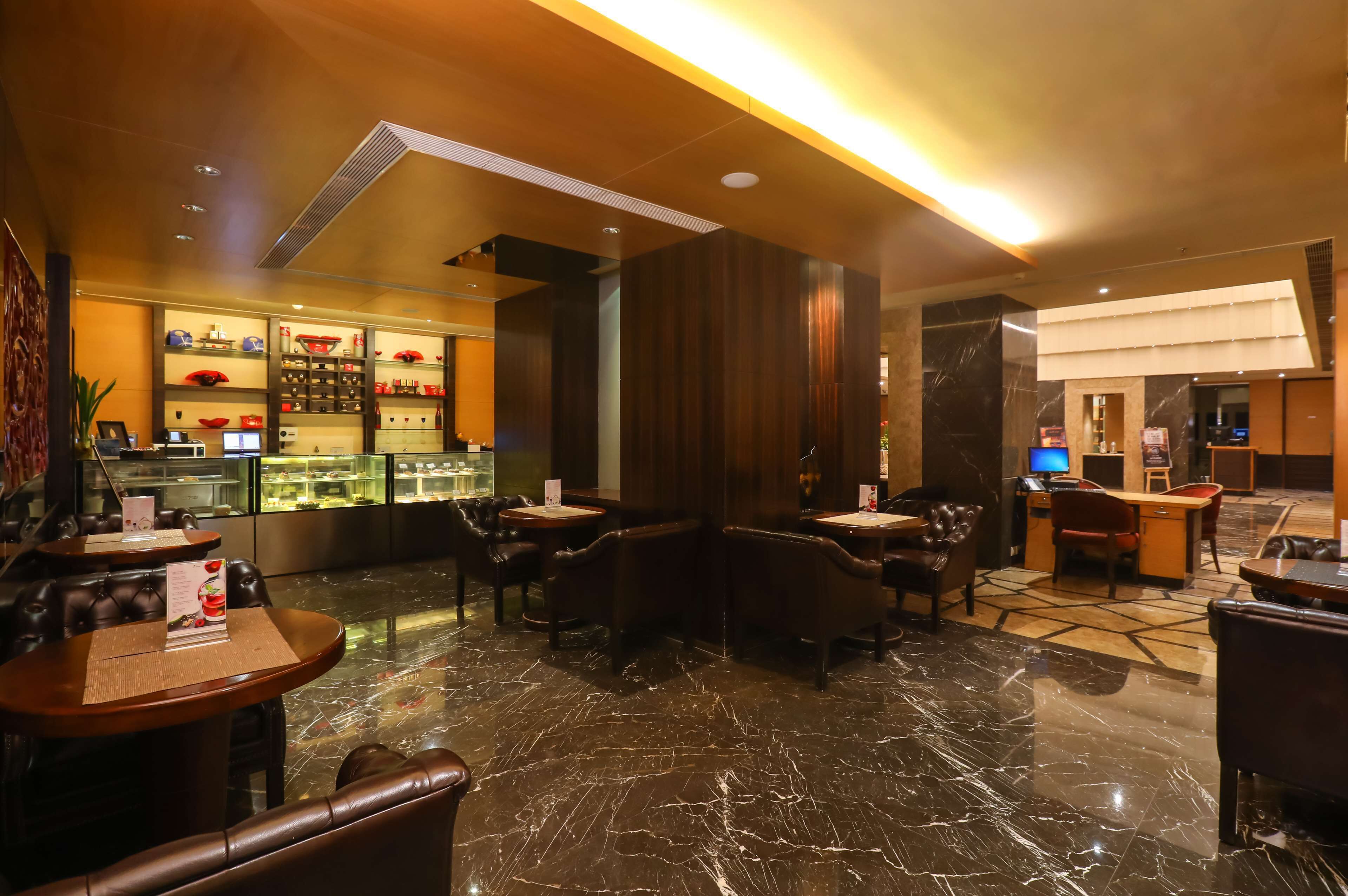 A hotel lobby with marble flooring, leather seating, a reception desk, and a display case with items.