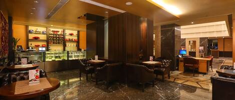 A hotel lobby with marble flooring, leather seating, a reception desk, and a display case with items.