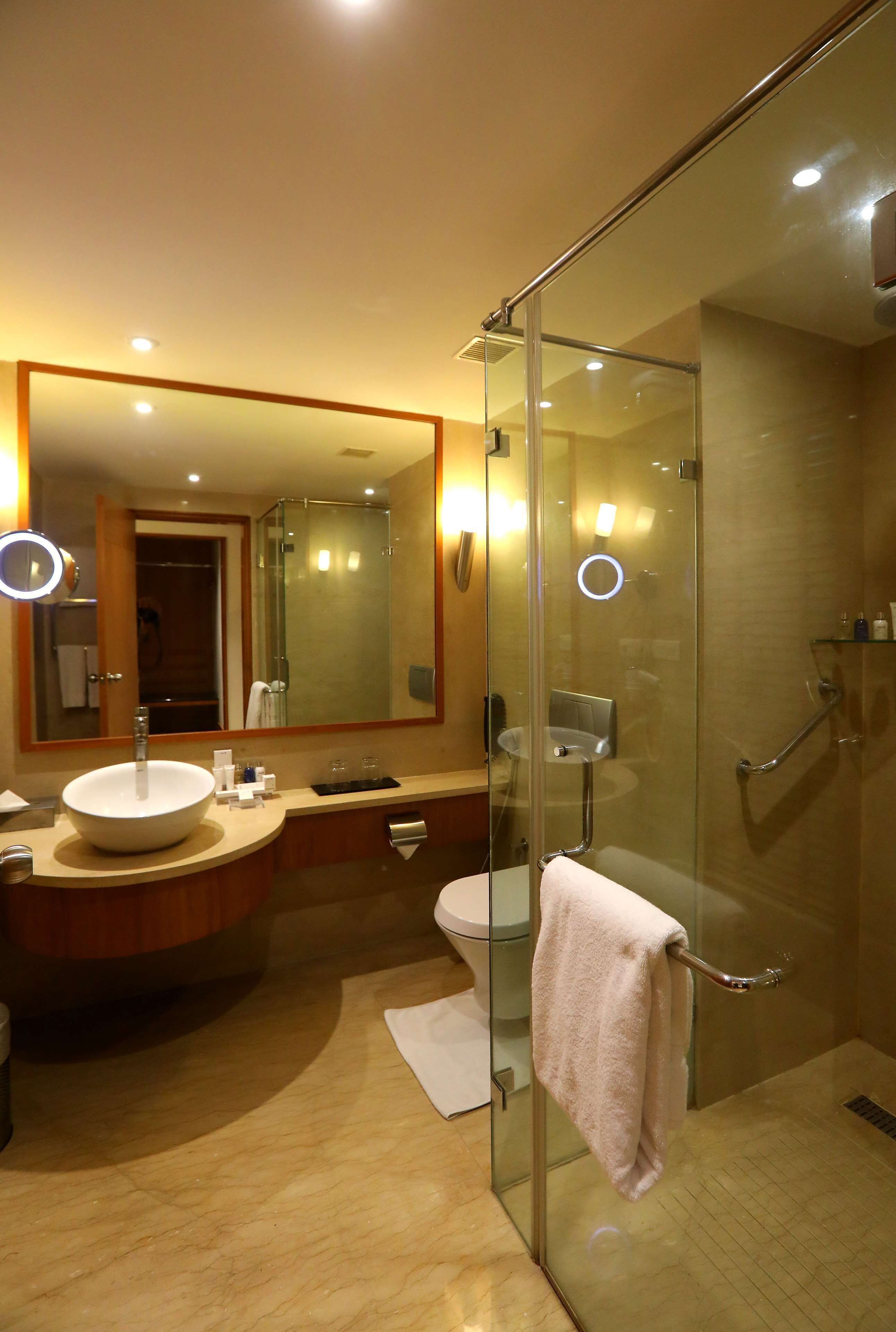 A modern bathroom with a glass-enclosed shower, a large mirror, and a round sink.