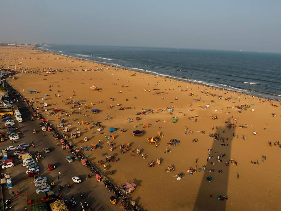 Une plage bordée d’une route, où l’on peut voir beaucoup de monde et de véhicules.