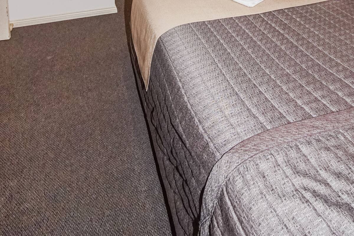 A hotel room with two beds, a flat-screen TV mounted on the wall, and a wooden headboard.
