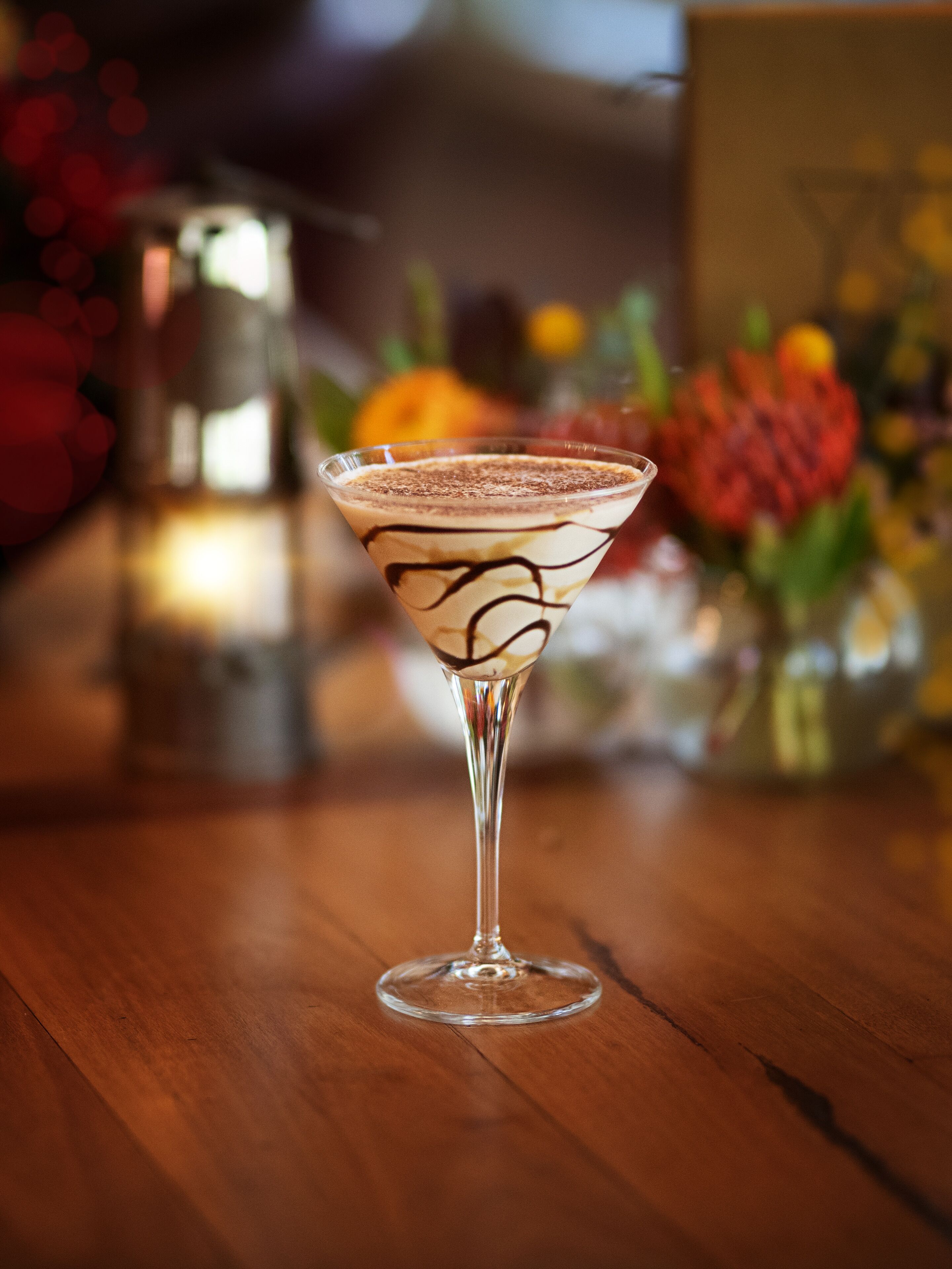 A martini glass with a chocolate swirl on a wooden table.