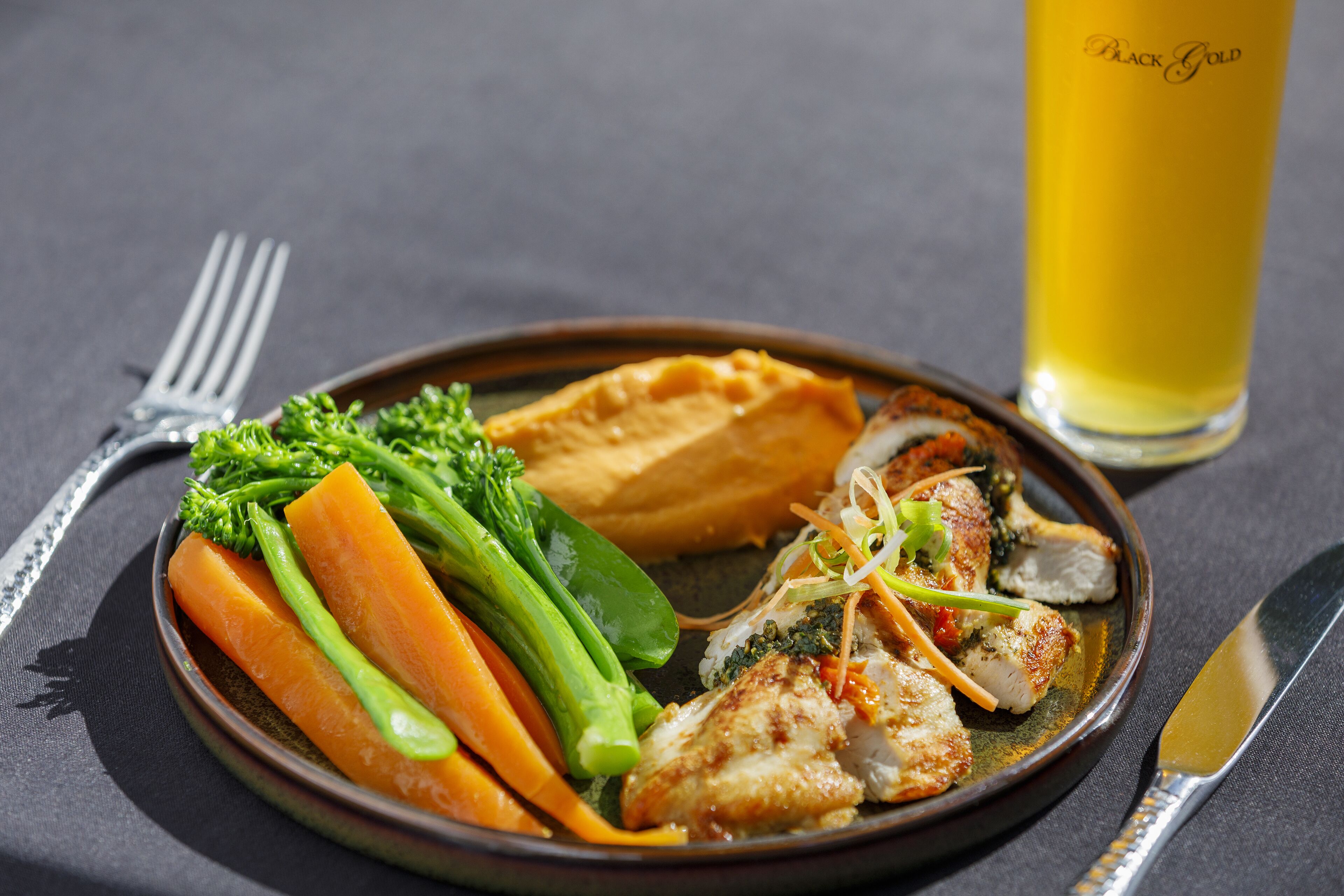 A plate of food with vegetables and a glass of beer.