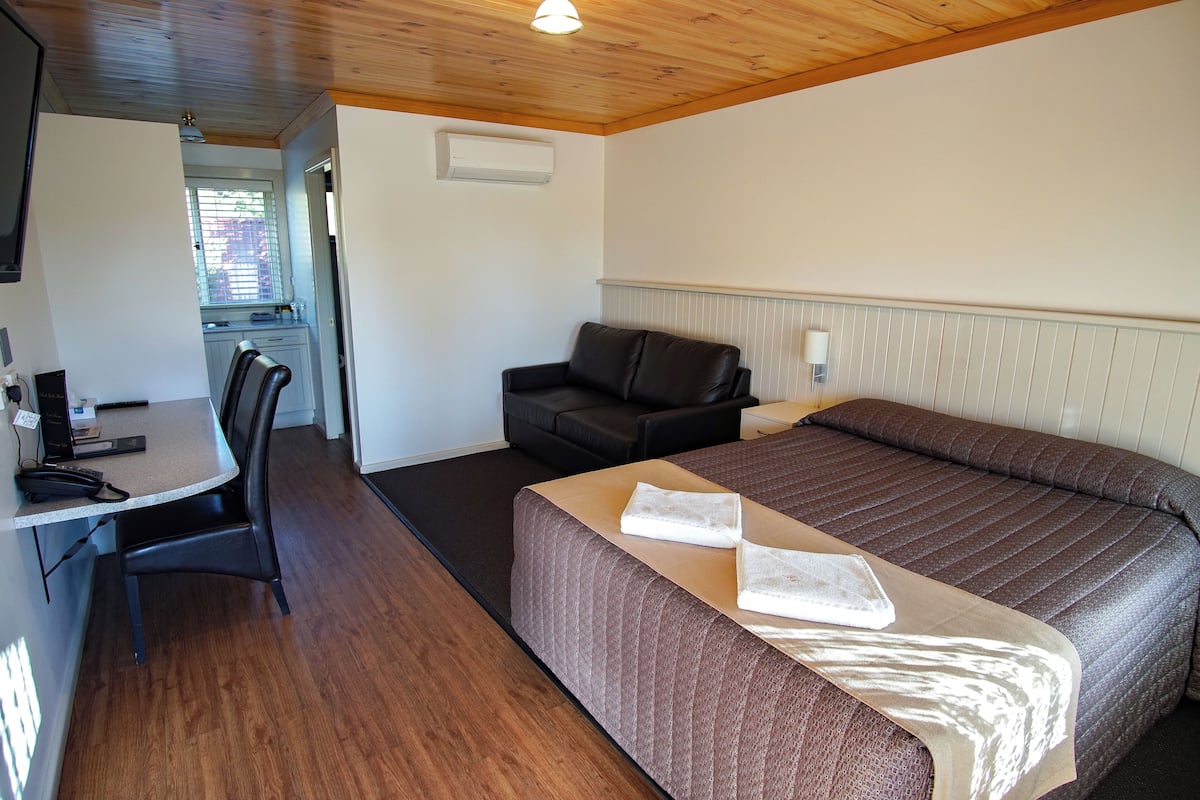 A room with a bed, a desk, a chair, and a sofa.