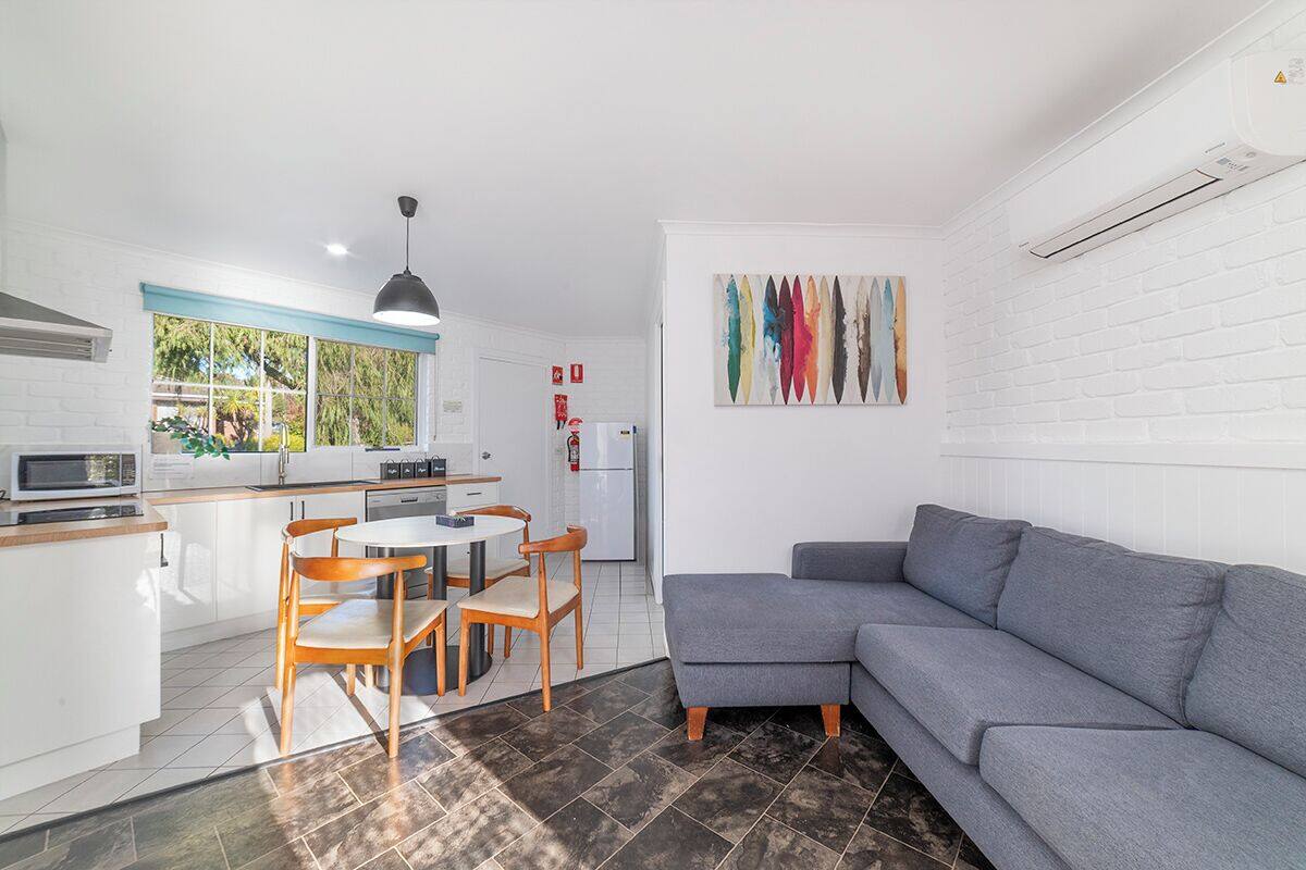 Ein kompakter Wohnbereich mit einer Küche, Essplatz und einem grauen Sofa.