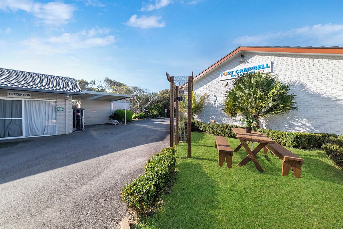 A hotel named "Port Campbell" with a reception area, a parking lot, and a picnic table in the foreground.