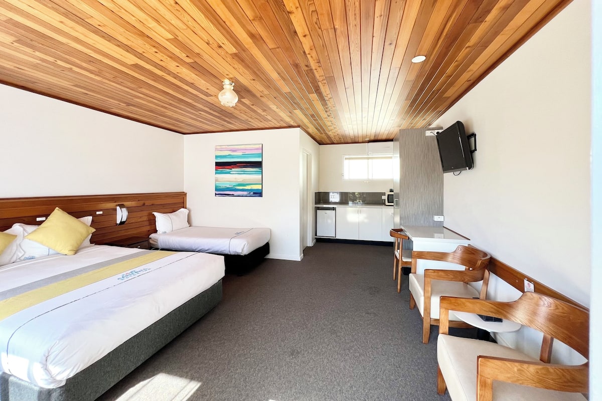 Ein Hotelzimmer mit zwei Betten, einer Küchenzeile und einer Sitzecke.