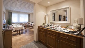 Quarto de hotel com área de refeições, armários de madeira e um espelho grande.