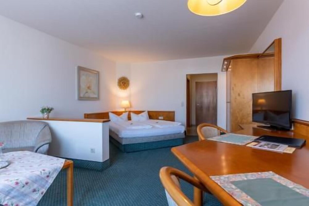 Una habitación de hotel con cama, escritorio, televisor y silla.