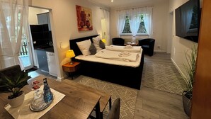 Quarto de hotel moderno com uma cama grande, mesas de cabeceira, uma escrivaninha e uma televisão.