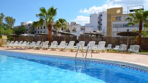 A swimming pool with lounge chairs and palm trees. - Aparhotel Vibra Central City - Adults Only (Sant Antoni de Portmany)