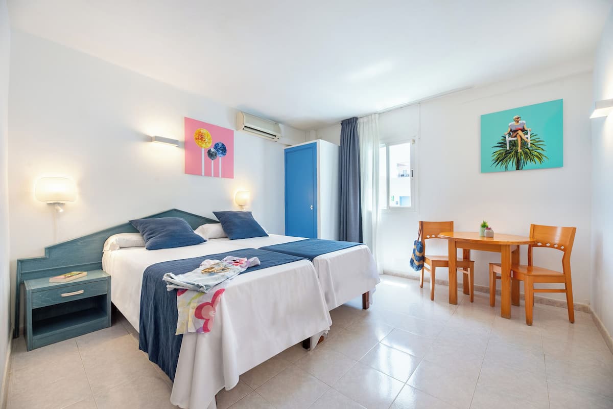 Ein Hotelzimmer mit Bett, Nachttisch, Lampe und einem kleinen Tisch mit Stühlen.