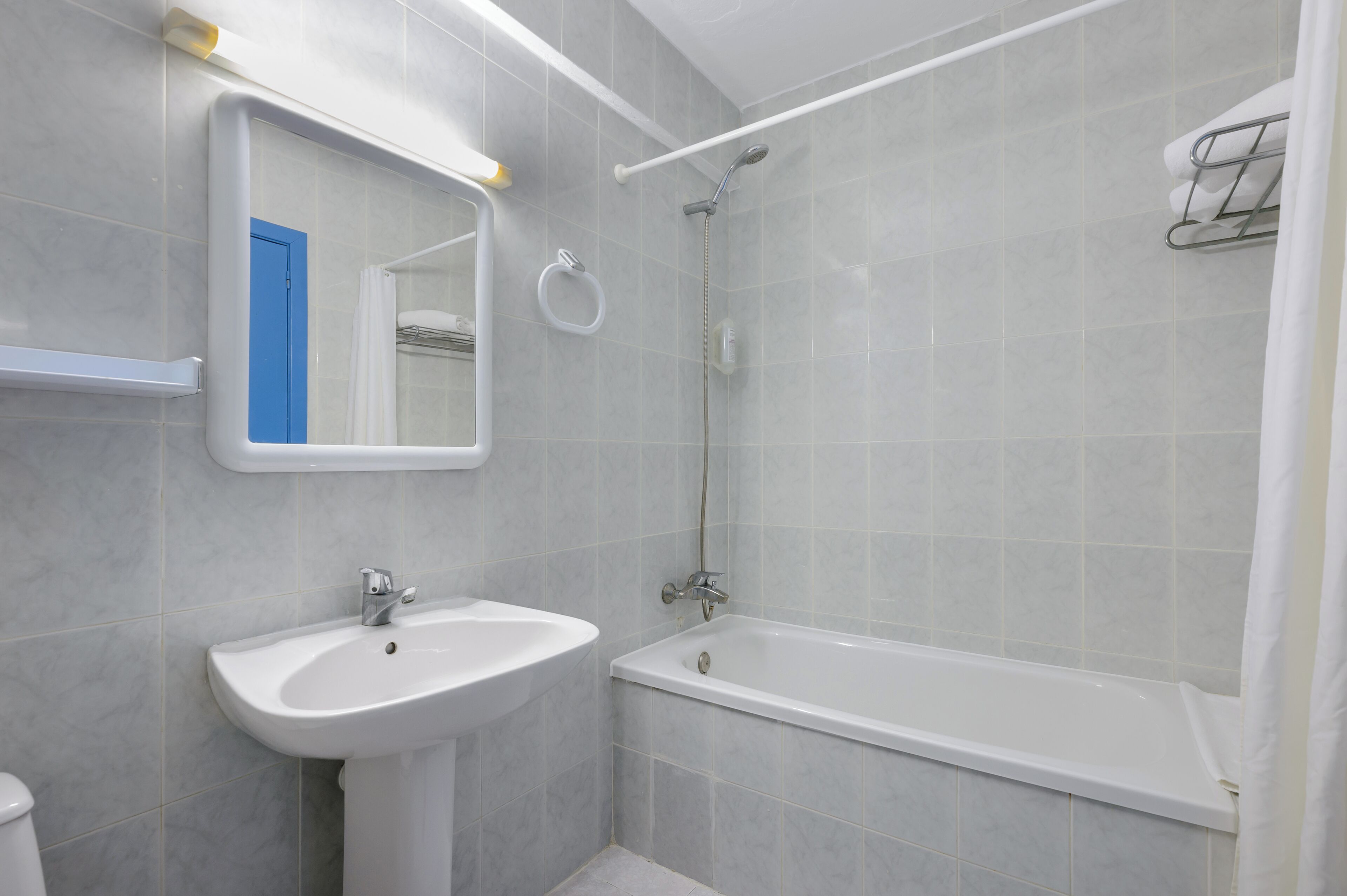 A bathroom with a sink, mirror, and bathtub.