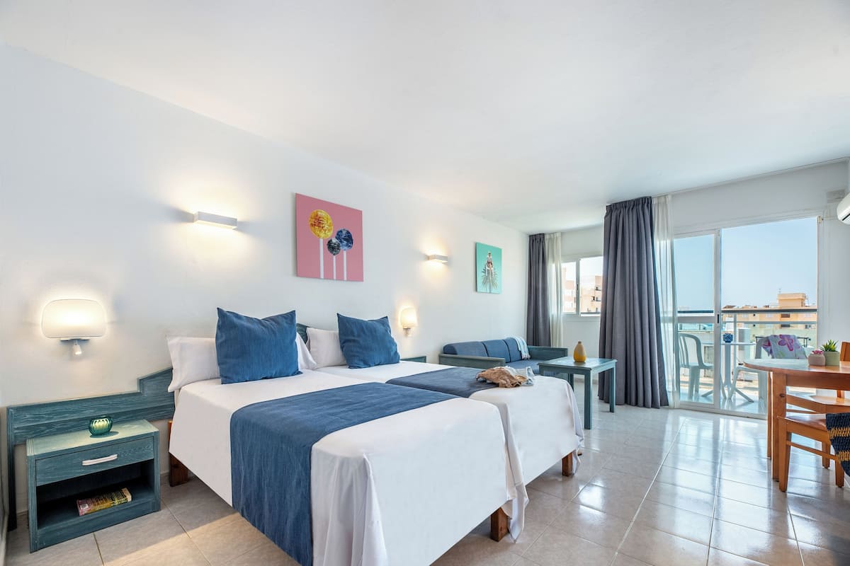 Ein Hotelzimmer mit zwei Betten, einem Balkon mit Aussicht und einem Essbereich.