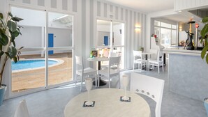 A modern hotel room with a pool view, white striped walls, and a bar area. - Aparhotel Vibra Central City - Adults Only (Sant Antoni de Portmany)