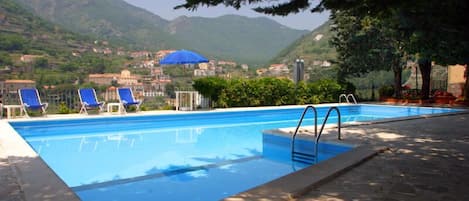 Una piscina al aire libre de temporada, sombrillas, tumbonas