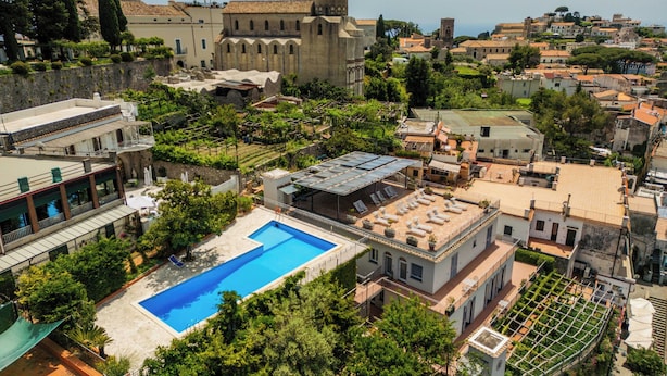 A rooftop pool with a view of historic buildings and a church in the background. - Residence Le Villette (Ravello)