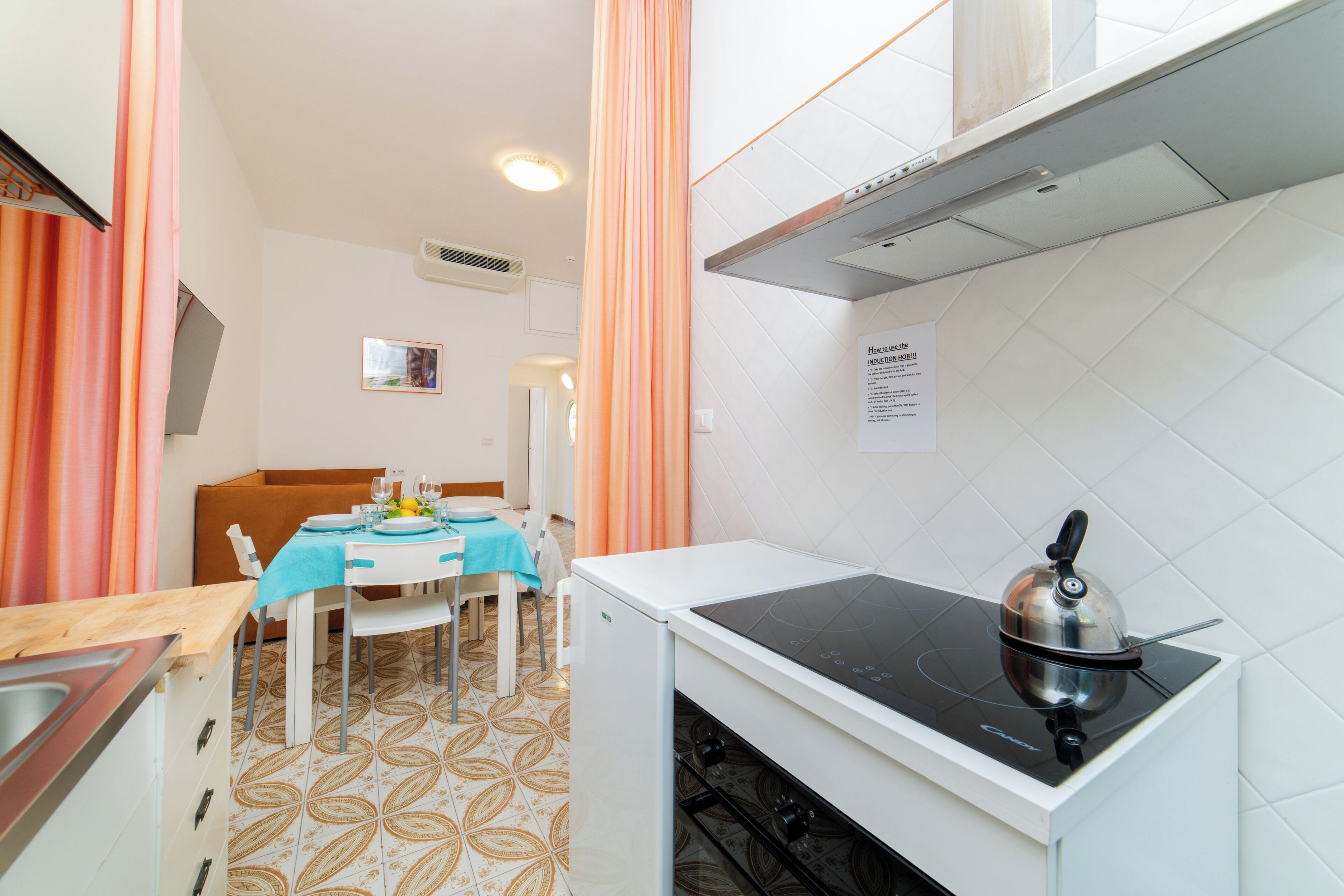 A compact kitchen with a stove, a dining table with chairs, and a small refrigerator.